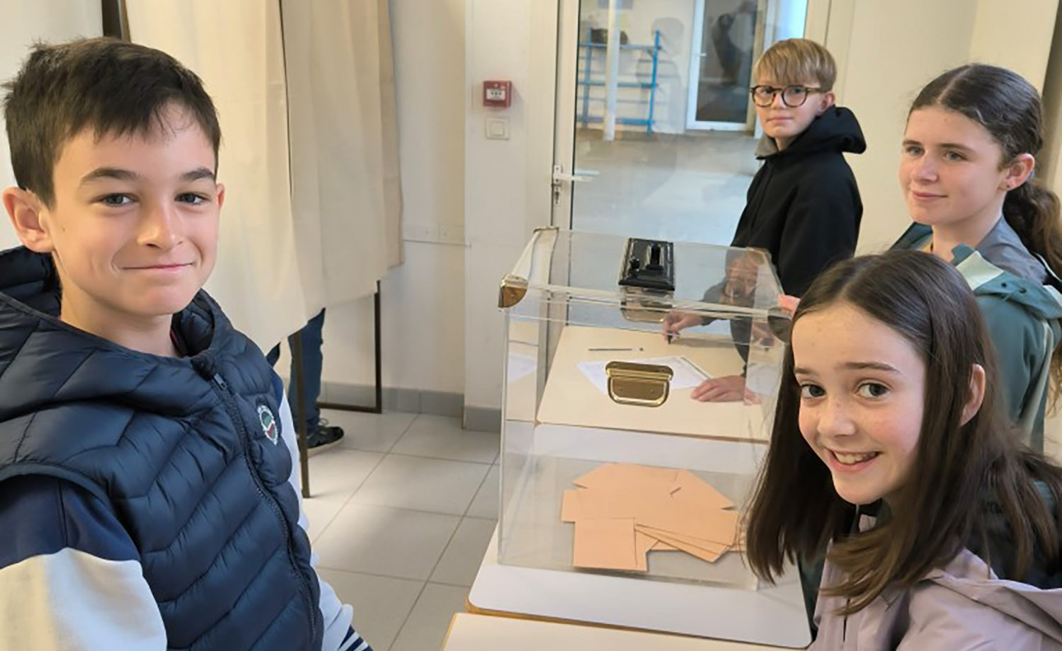 Des élèves de 6ème en train de participer activement aux élections de leurs délégués de classe, devant des urnes et des isoloirs dans un cadre scolaire.