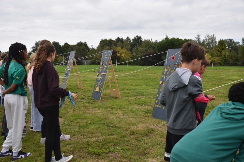 Collégiens concentrés pour relever un défi collectif à l’extérieur.