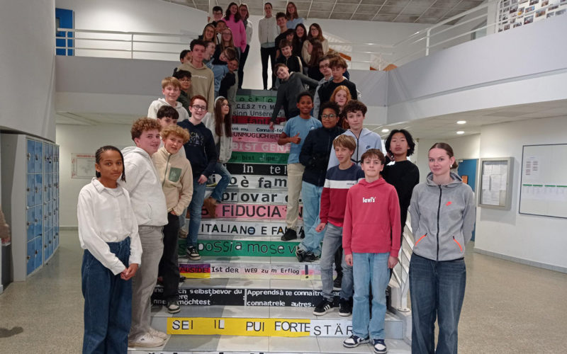 Élèves du Collège Immaculée installant des phrases multilingues sur les marches de l’escalier dans le cadre du projet "Les marches de la réussite".